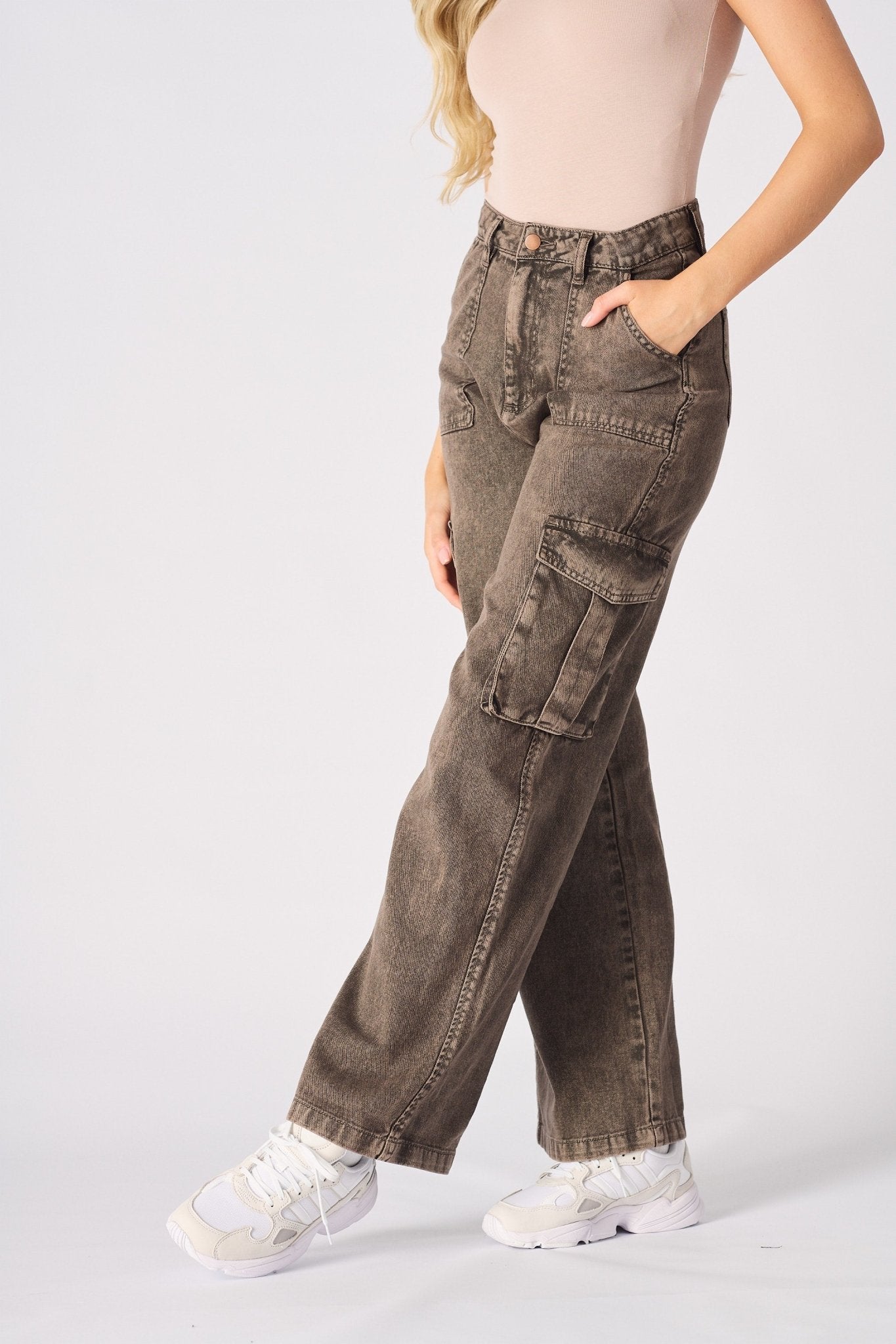 An angled shot of the model wearing brown cargo jeans for women focusing on the functional side pockets.