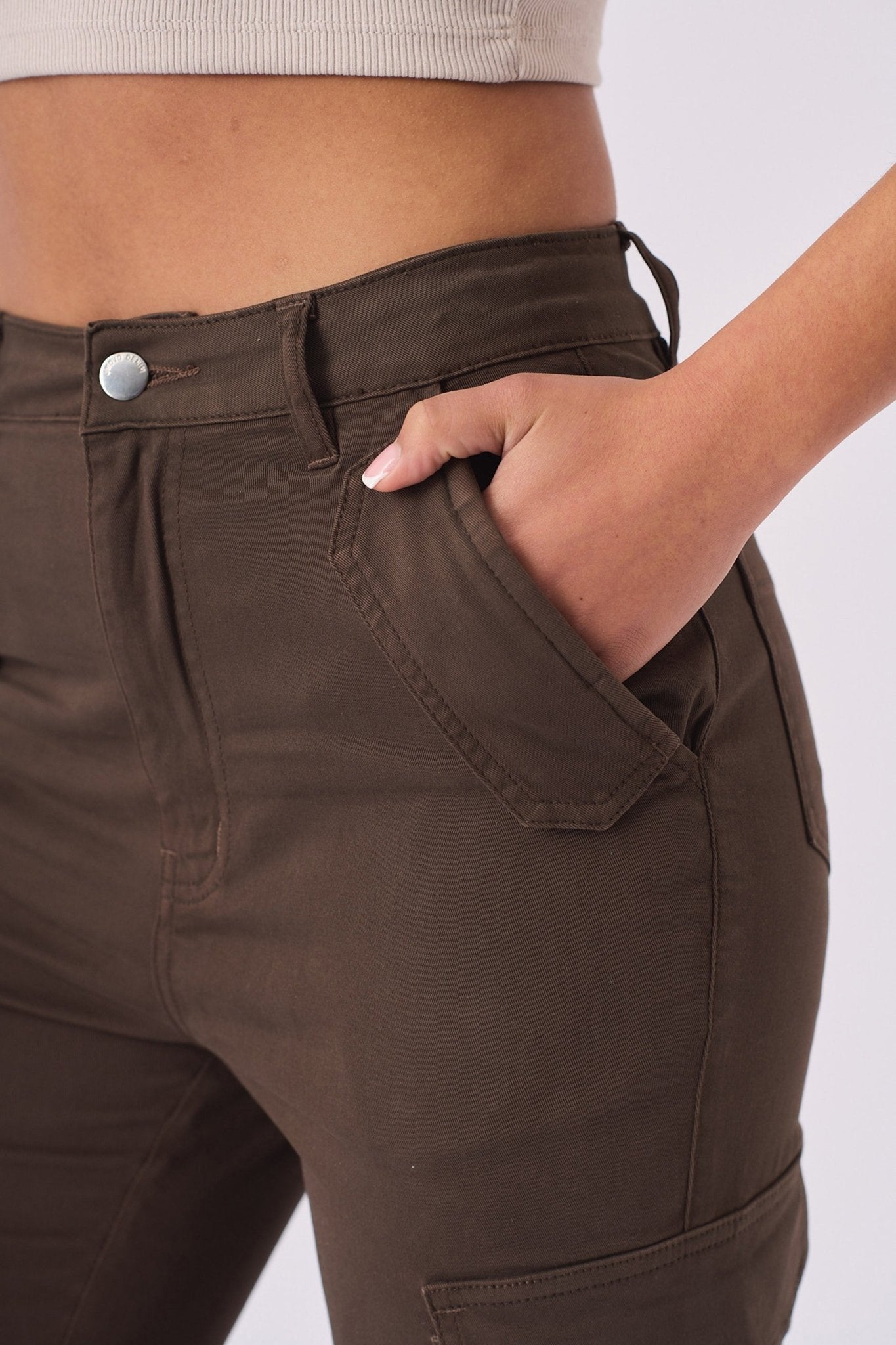 Close up shot of a hand in the front pocket of the brown cargo jeans showing fabric texture.
