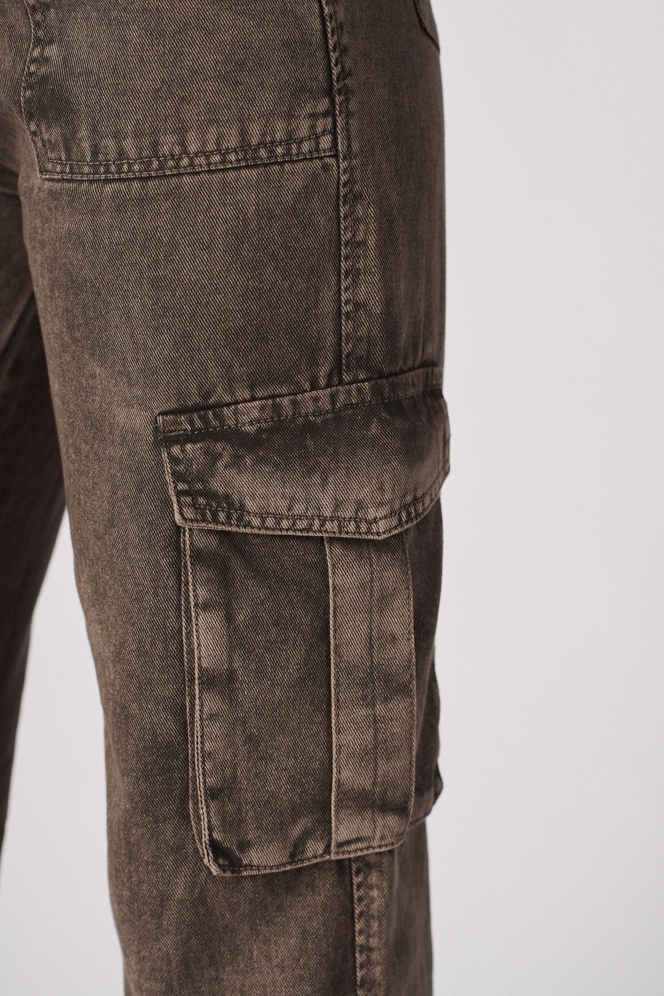 A detailed view of a cargo-style pocket on the durable brown denim fabric.