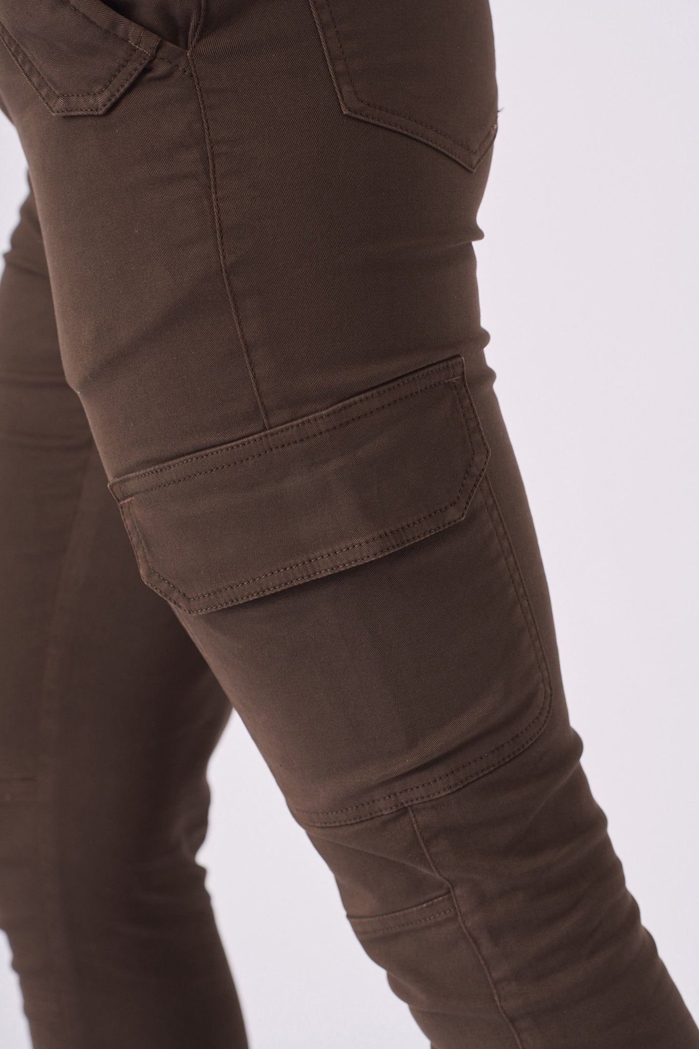 A zoomed in view of the functional side cargo pocket on the rich brown denim material.