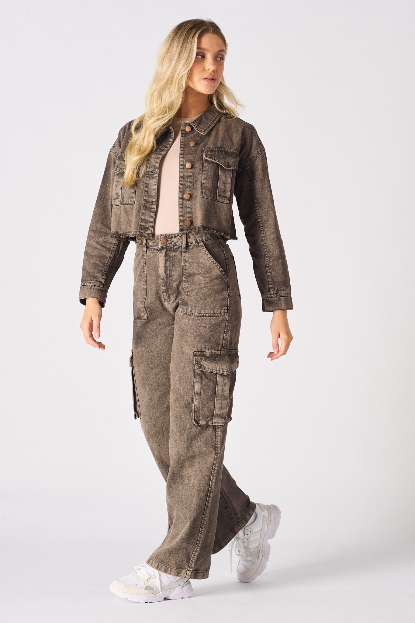 A model walking in brown cargo jeans for women styled with white trainers and a beige top.