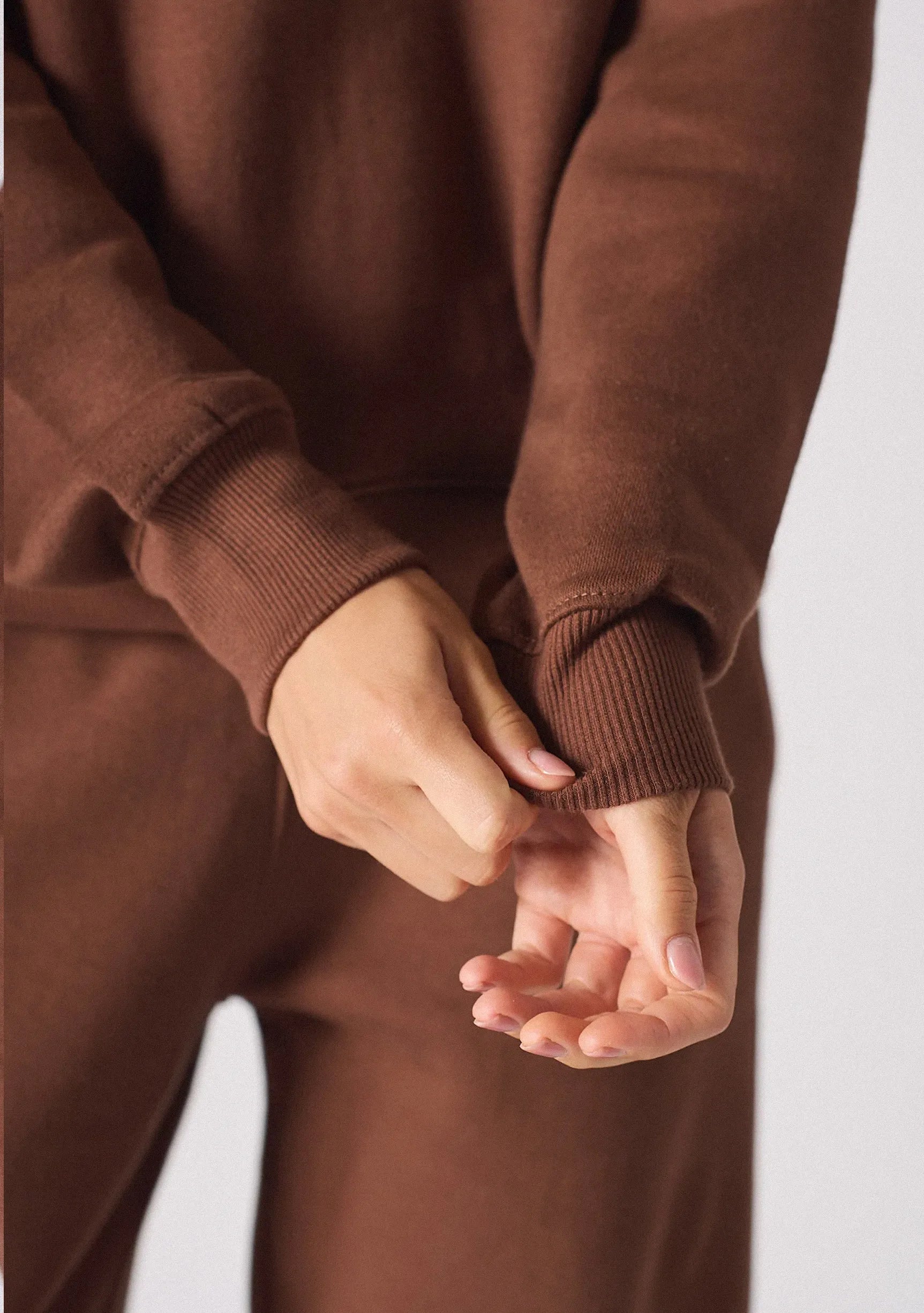 Detailed view of the ribbed cuffs on a brown crew neck jumper
