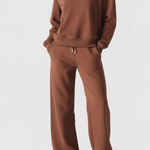 Full front view of a woman wearing a chocolate brown crew neck jumper and matching trousers