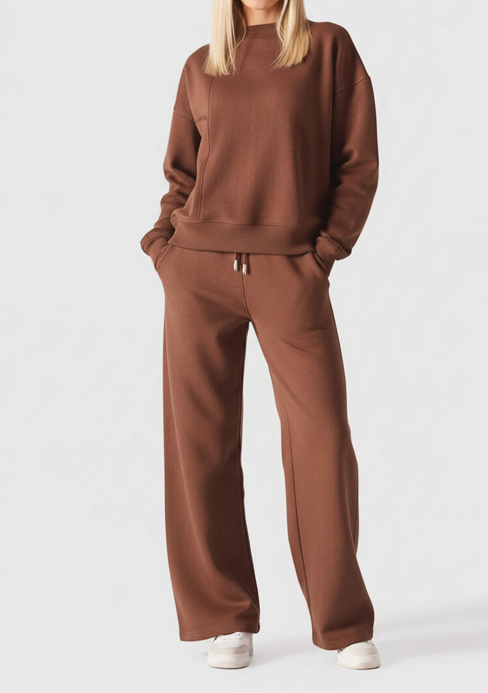 Full front view of a woman wearing a chocolate brown crew neck jumper and matching trousers