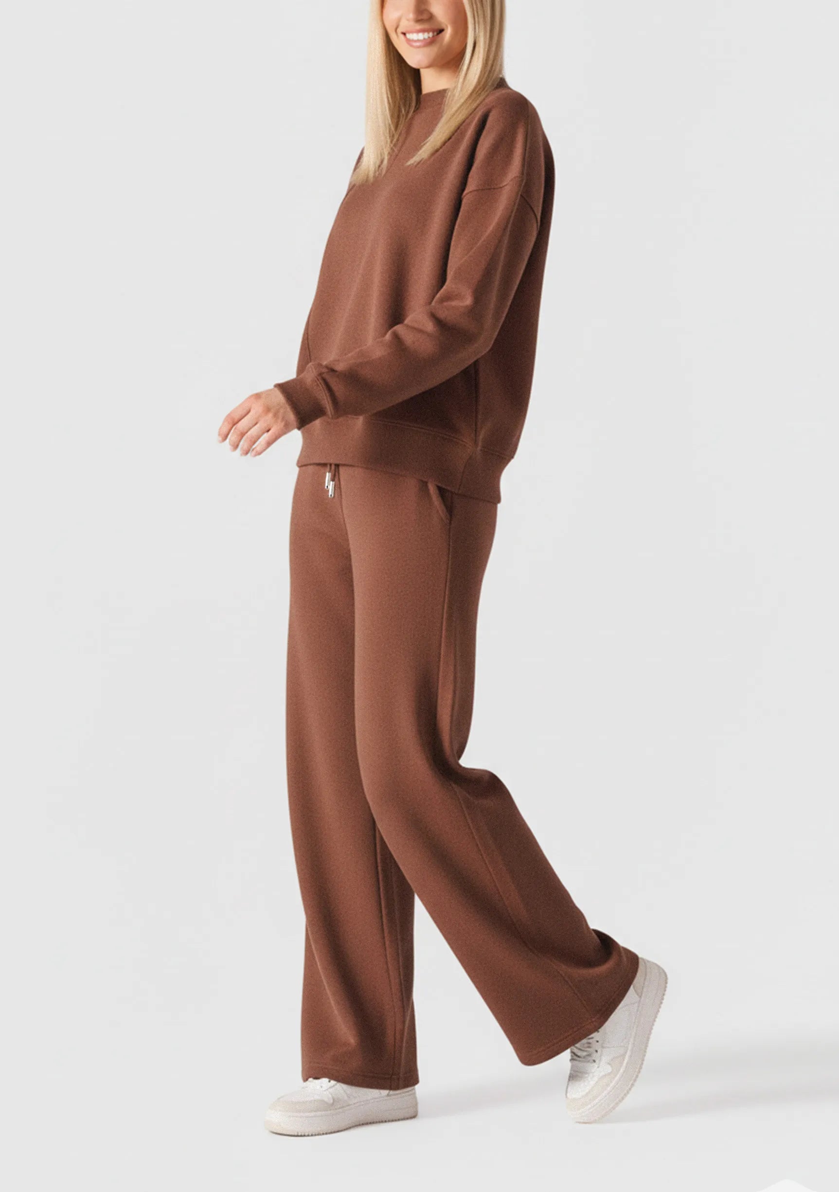 Side view of a woman walking in a chocolate brown crew neck jumper