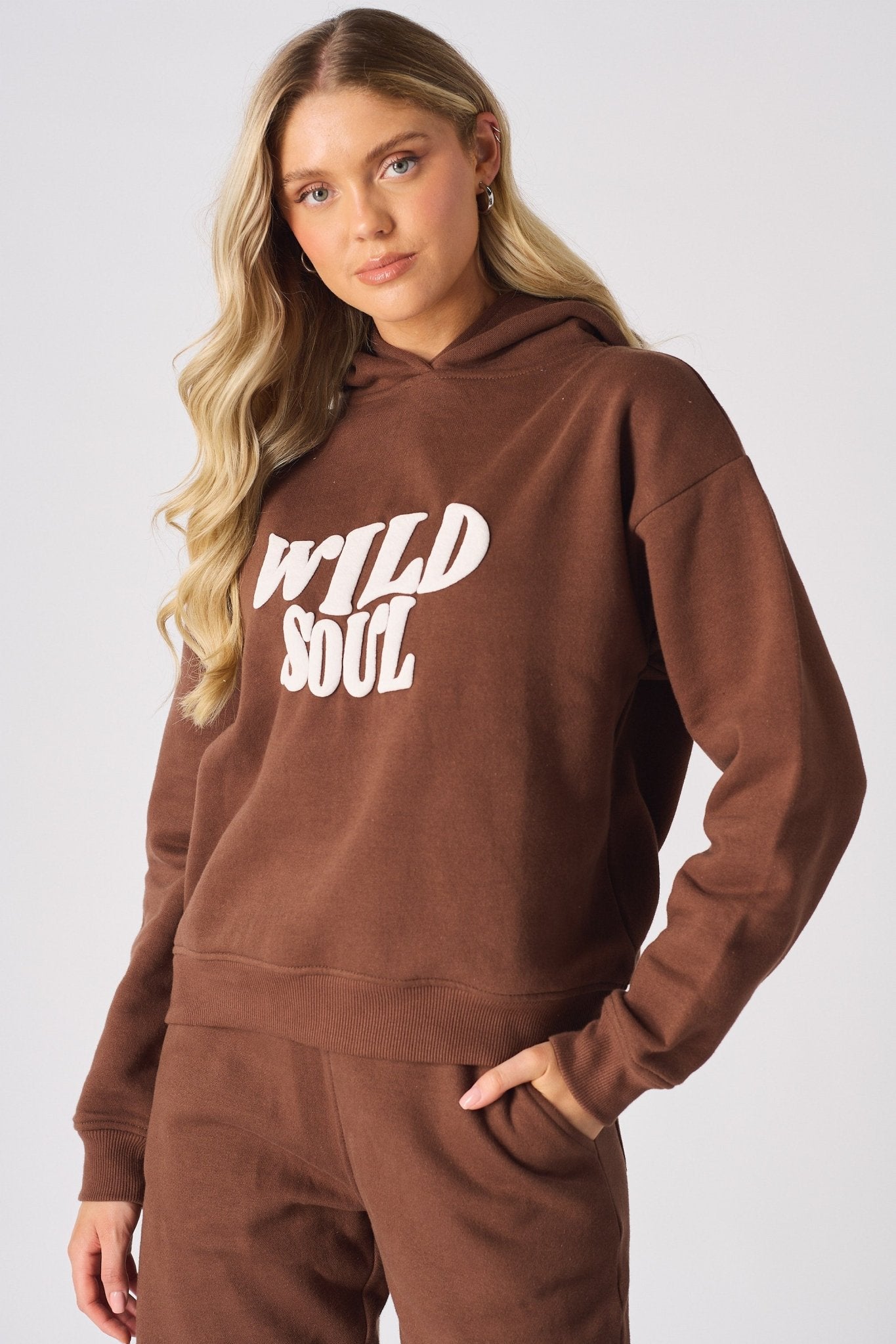Close up front view of a brown hoodie showing the bold white wild soul puff print