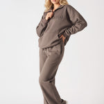 A model posing in the oversized brown quarter zip sweatshirt for a casual look.