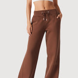 A front view of a woman wearing chocolate brown wide leg joggers with a white top