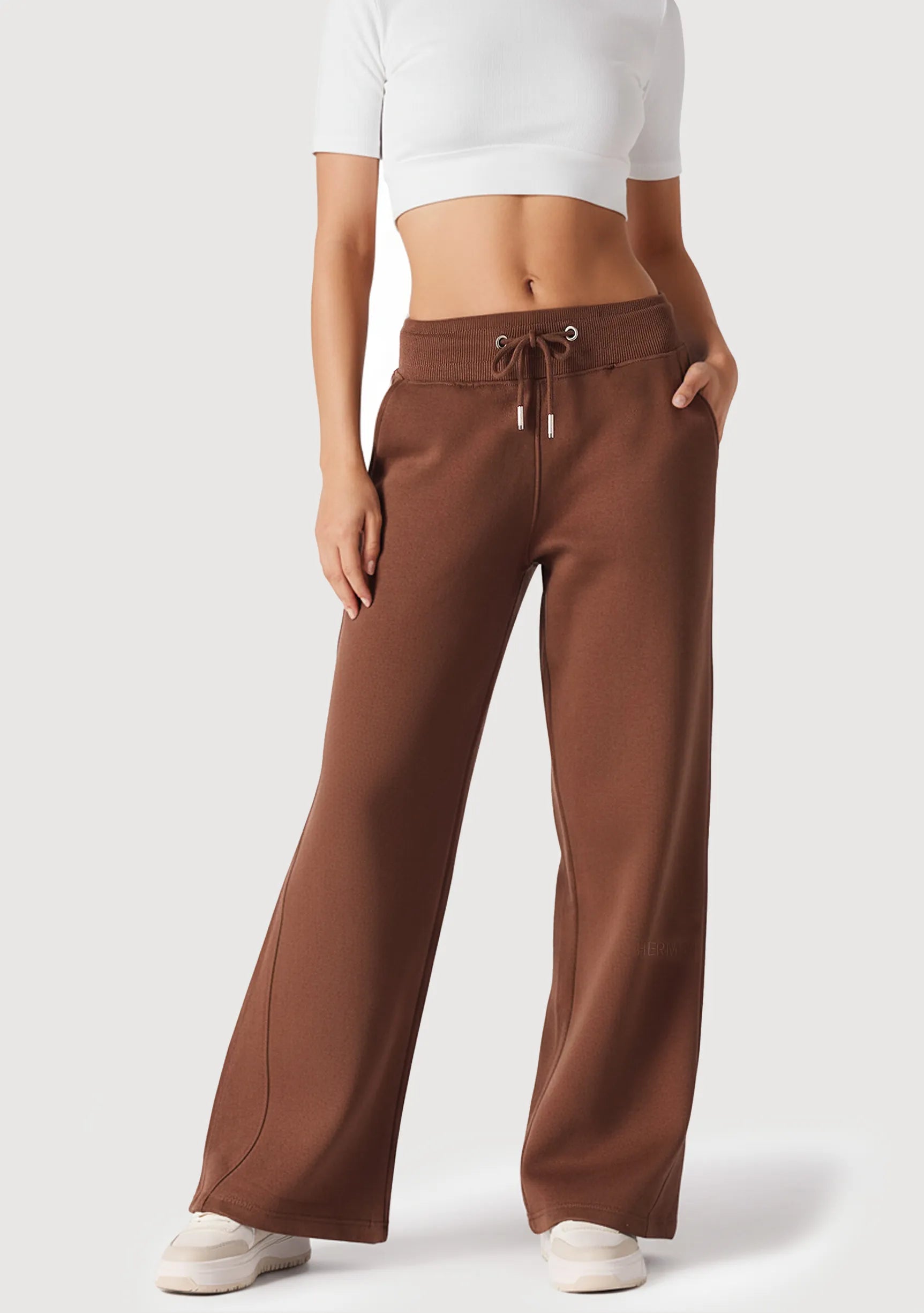 A front view of a woman wearing chocolate brown wide leg joggers with a white top