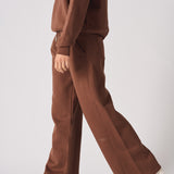 Side view of a woman walking in chocolate brown wide leg joggers and a matching jumper