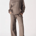 Full body view of a model in brown wide leg joggers women and a matching hoodie.