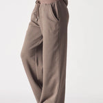 A woman wearing brown wide leg joggers women in a stylish side view.