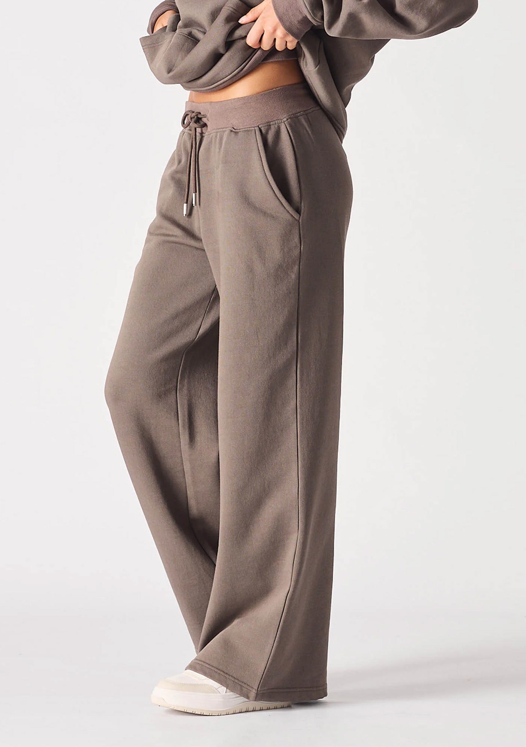 A woman wearing brown wide leg joggers women in a stylish side view.