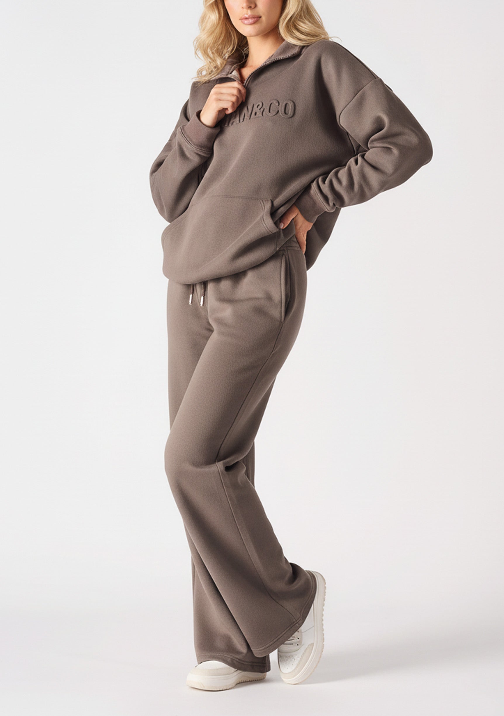 A model posing in premium brown wide leg joggers women with white trainers.