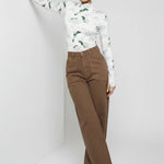 Model leaning against a wall wearing high-waisted mocha brown utility pants