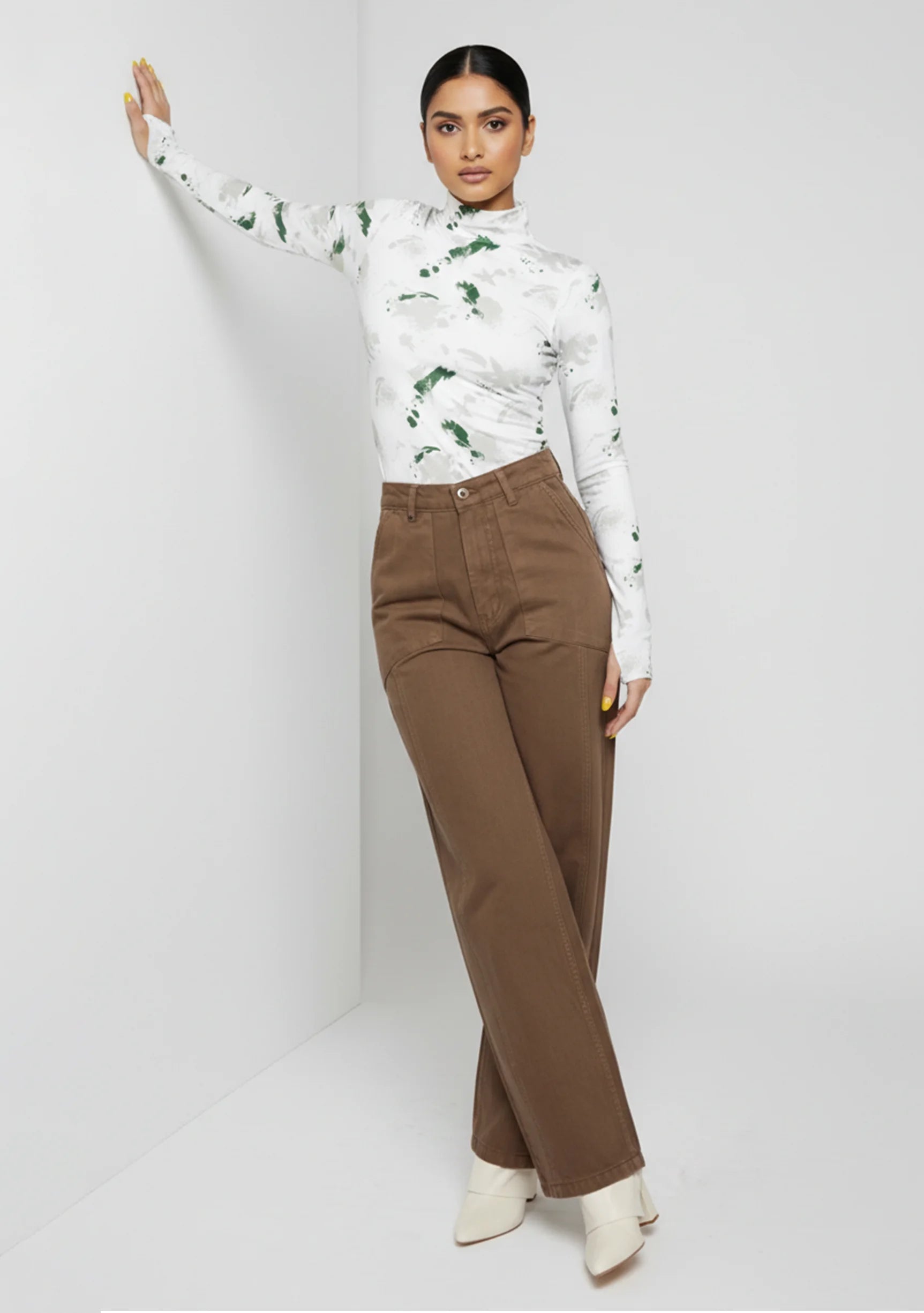 Model leaning against a wall wearing high-waisted mocha brown utility pants