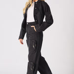 A model wearing black cargo jeans for women with a matching denim jacket and white trainers.