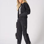 Profile view of the model wearing the black straight-leg cargo jeans and denim jacket.