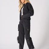 Profile view of the model wearing the black straight-leg cargo jeans and denim jacket.