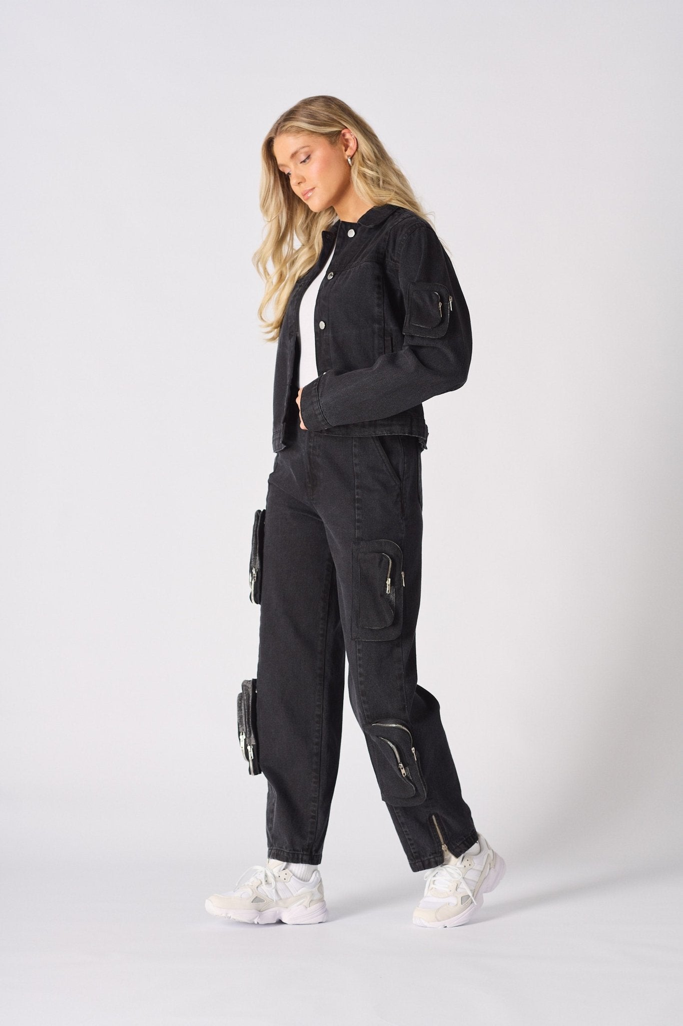 Profile view of the model wearing the black straight-leg cargo jeans and denim jacket.
