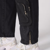 Detailed shot of the utility pocket and unique zip system on the black cargo jeans.