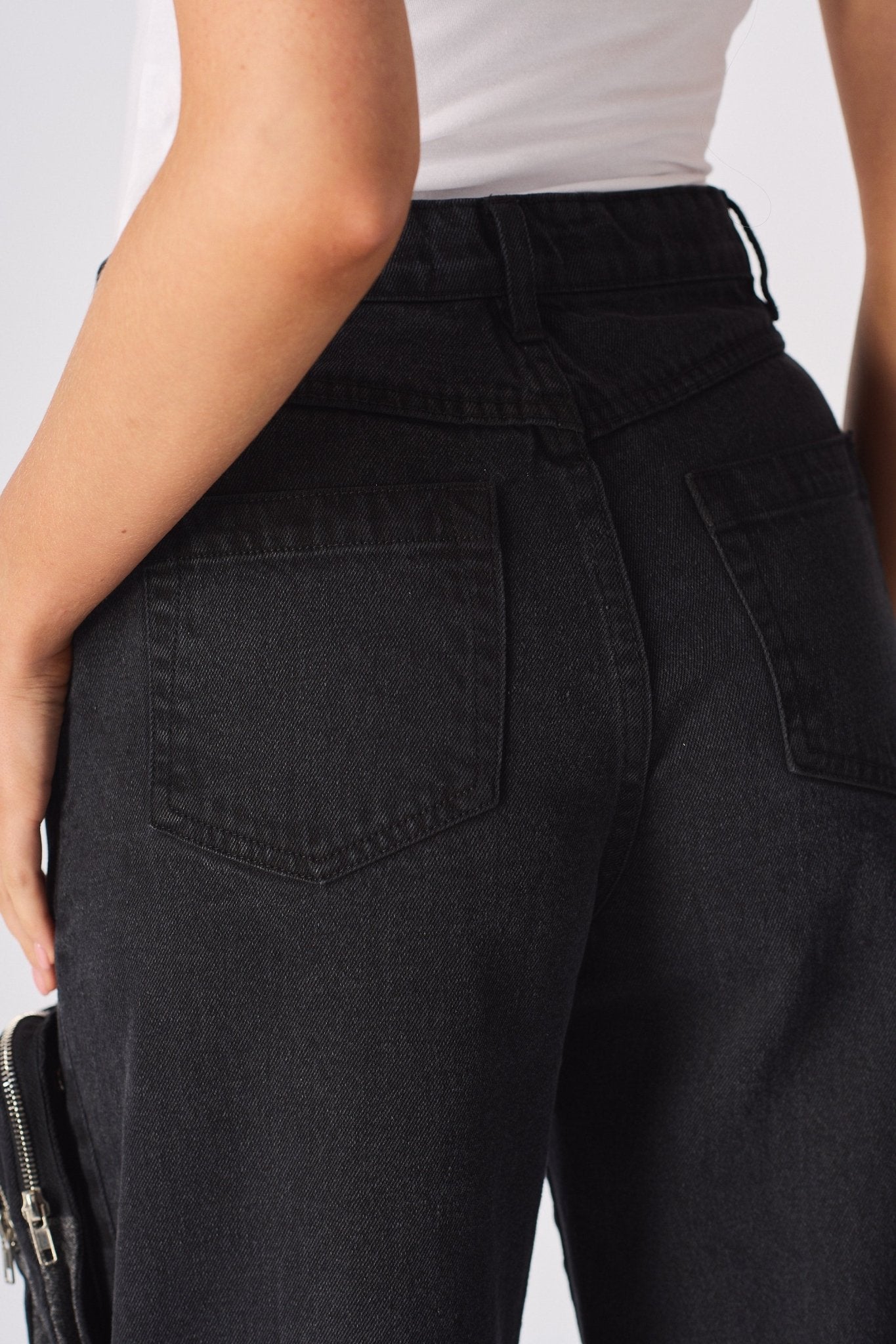 Back view of the high-waisted black cargo jeans showing pocket placement and denim finish.