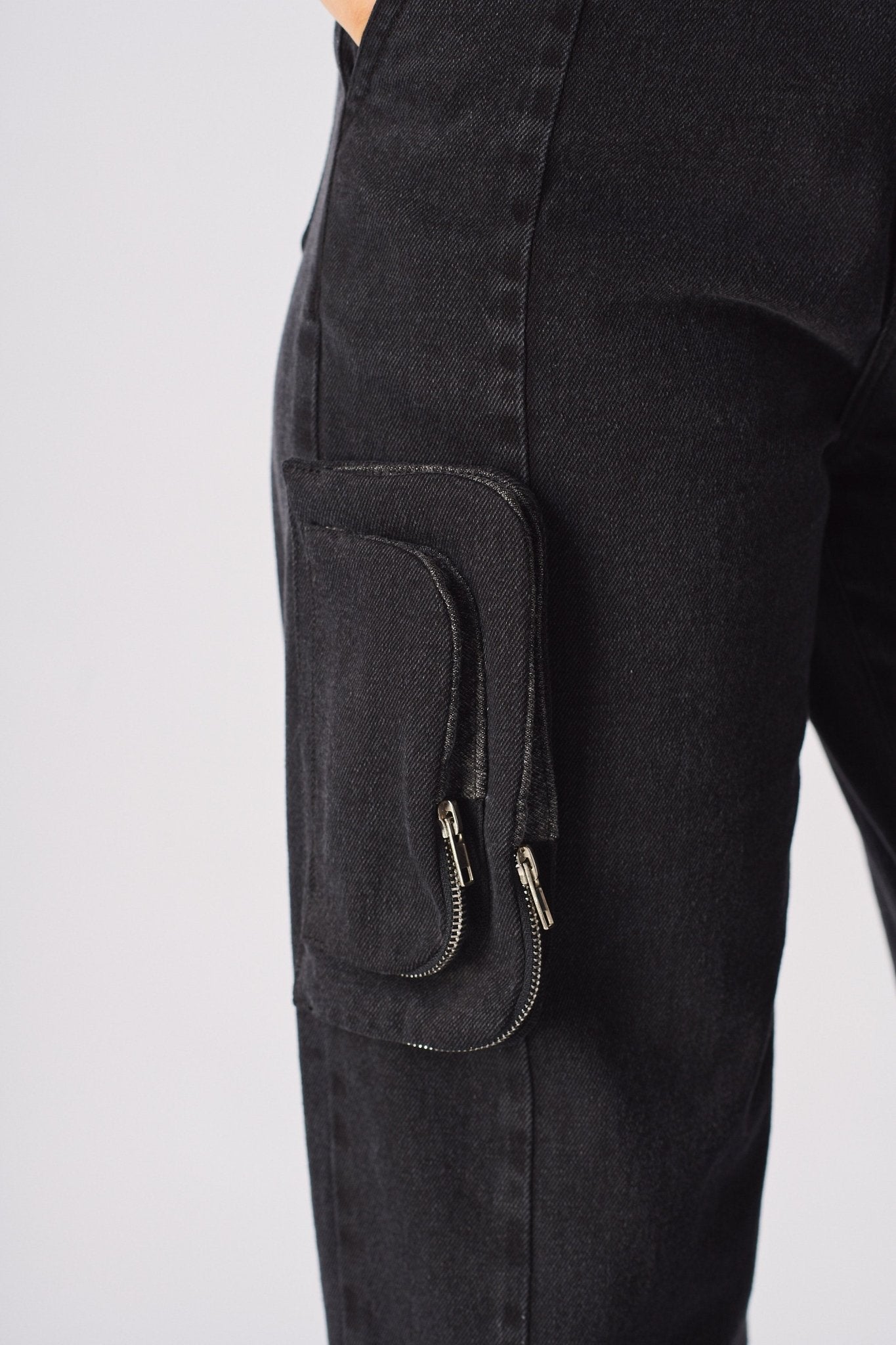 A close up of the side pocket on the black cargo jeans showing the zip attachment.