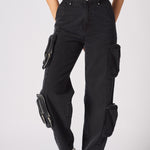 A close up shot of the removable zip off pockets on the black cargo jeans for women.