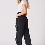 A woman walking to show the movement and relaxed fit of the black cargo jeans.