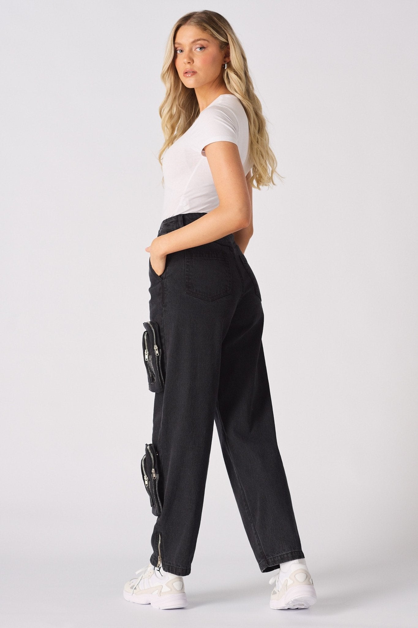 A woman walking to show the movement and relaxed fit of the black cargo jeans.