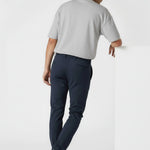 Man leaning against a white block wearing stylish casual blue chinos.