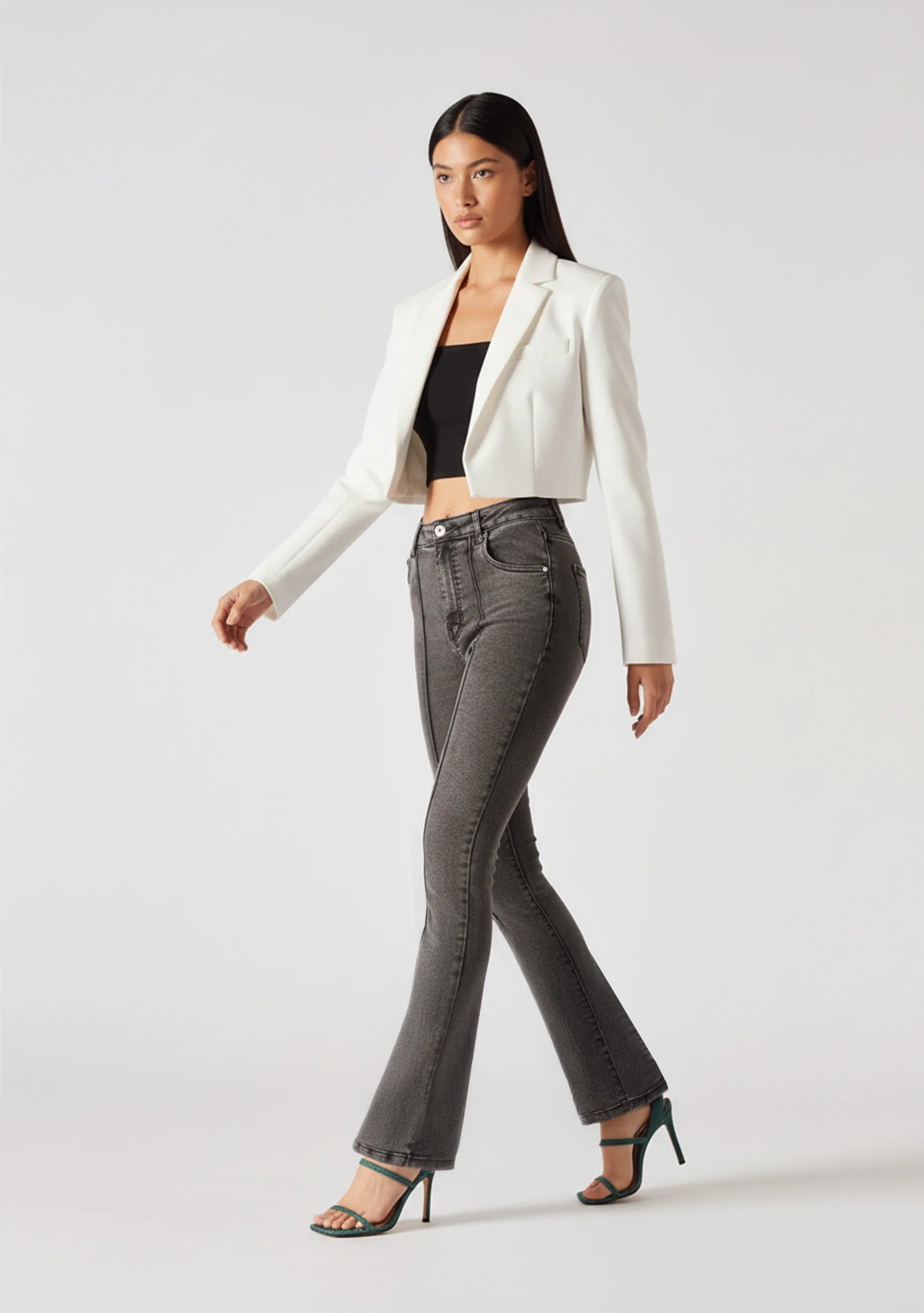 Side-front view of model walking in women's charcoal grey high-waisted bootcut jeans