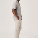 Side profile of a man posing with hands in pockets in flexible cream chinos mens.