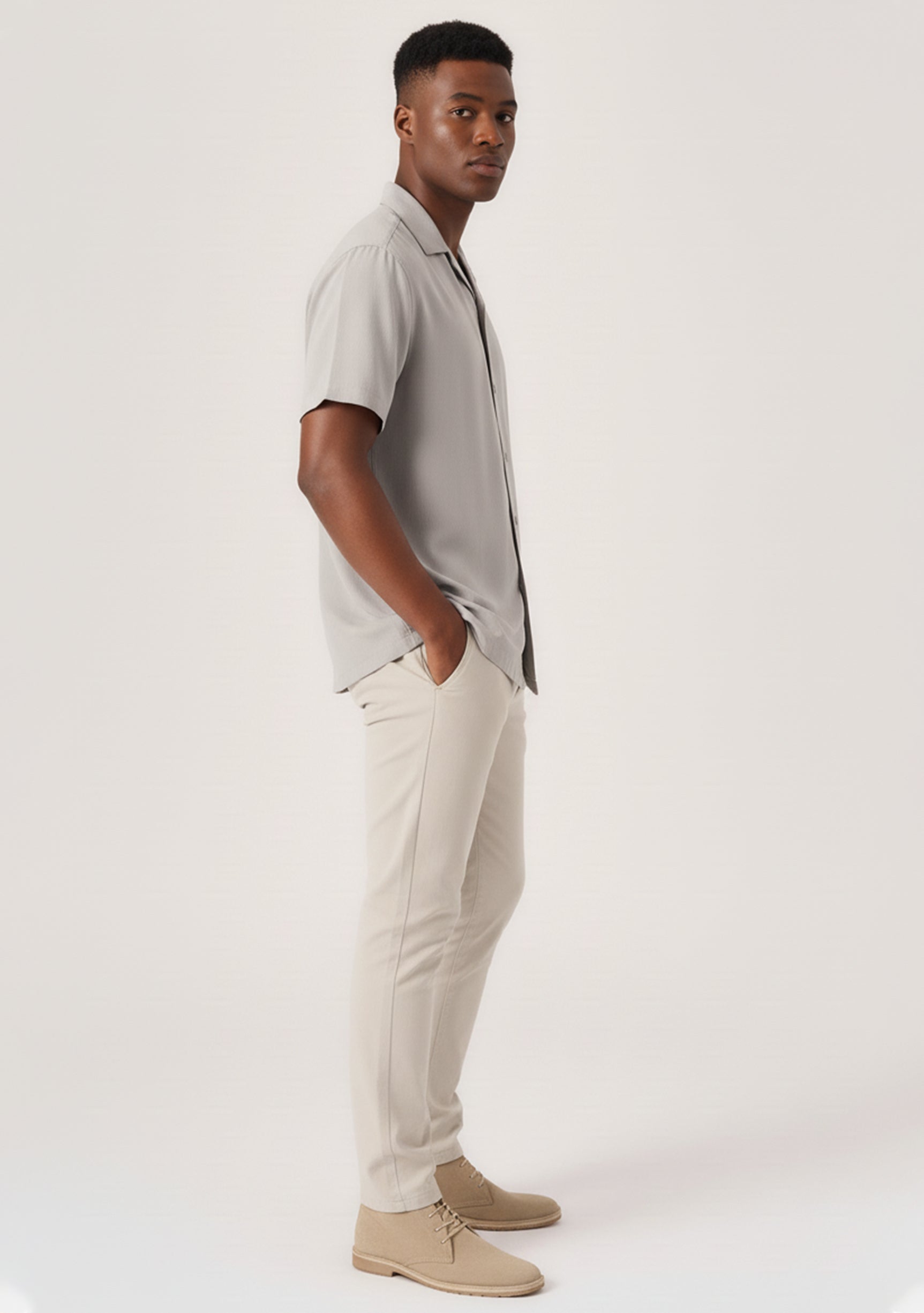 Side profile of a man posing with hands in pockets in flexible cream chinos mens.