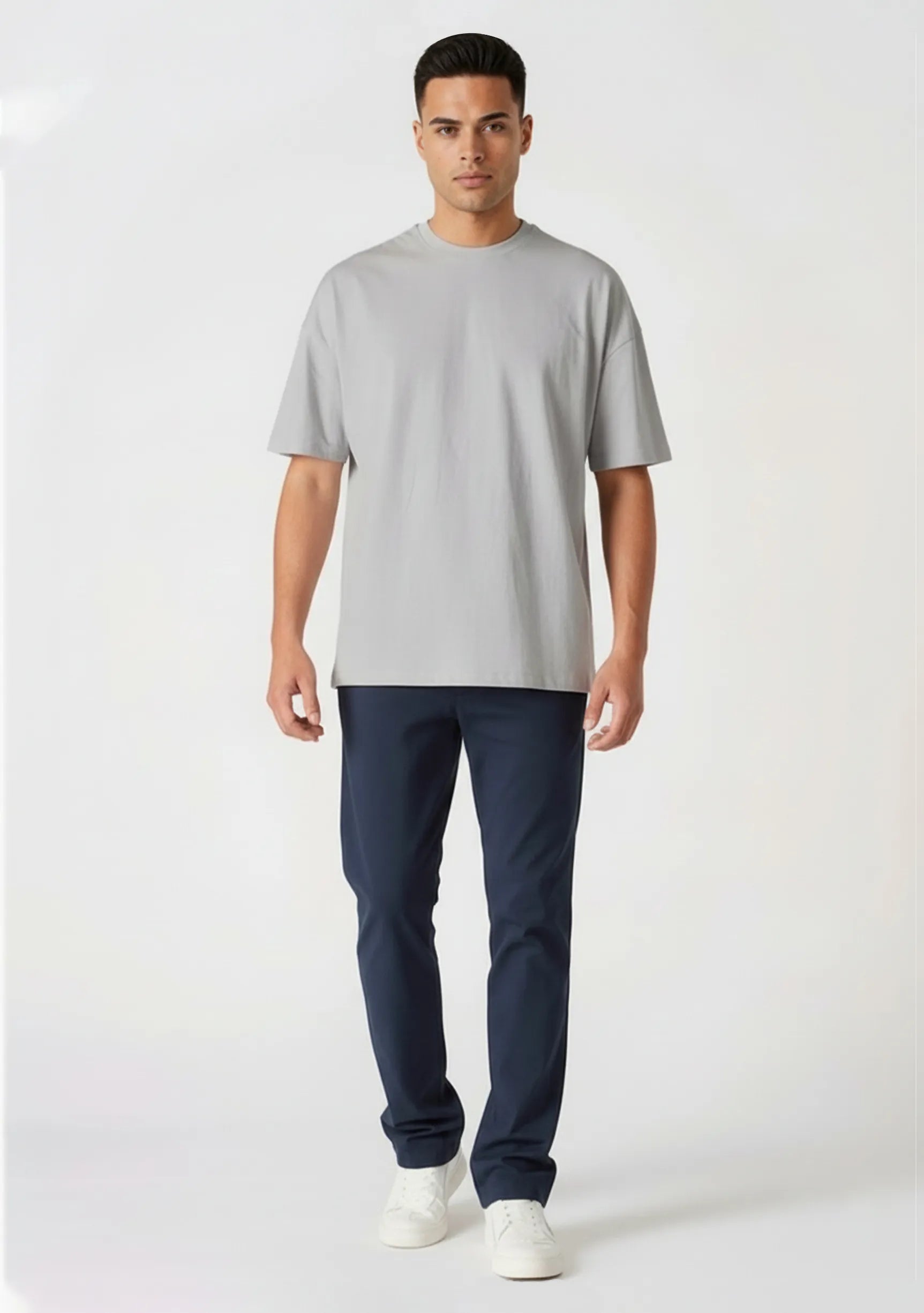 Handsome model walking forward wearing casual dark blue chinos for men.