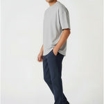 Side profile of a man walking casually in stretch dark blue chinos.