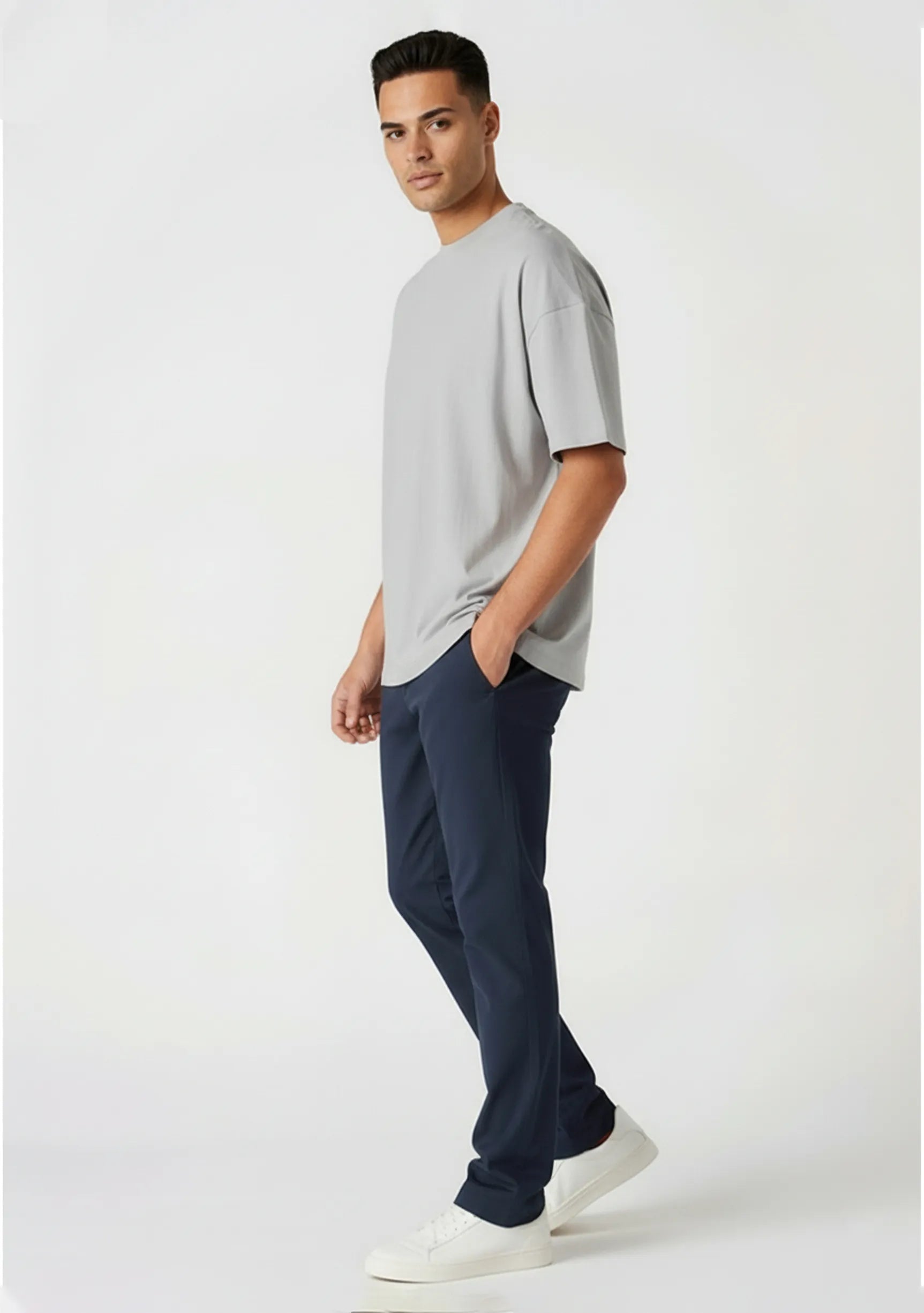 Side profile of a man walking casually in stretch dark blue chinos.
