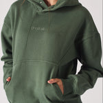 Mid shot showing the relaxed fit and fabric of a dark green hoodie for women