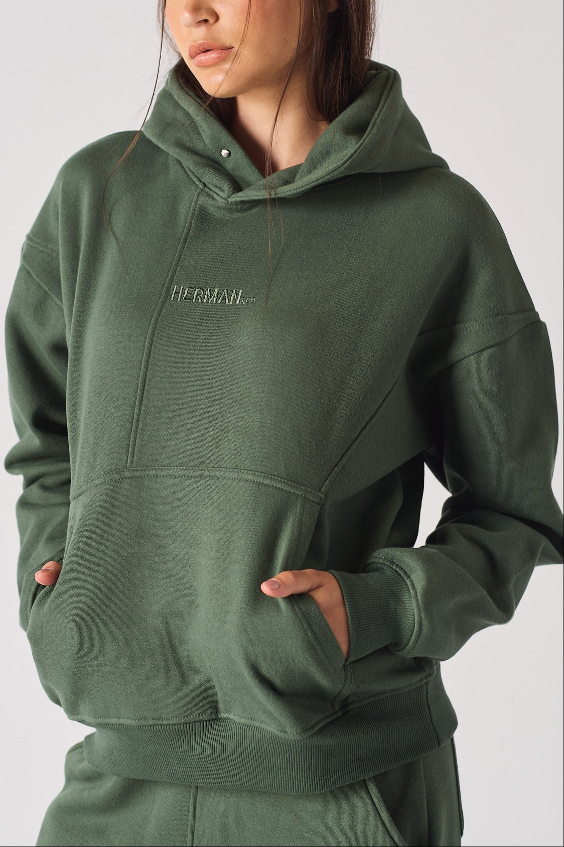 Mid shot showing the relaxed fit and fabric of a dark green hoodie for women