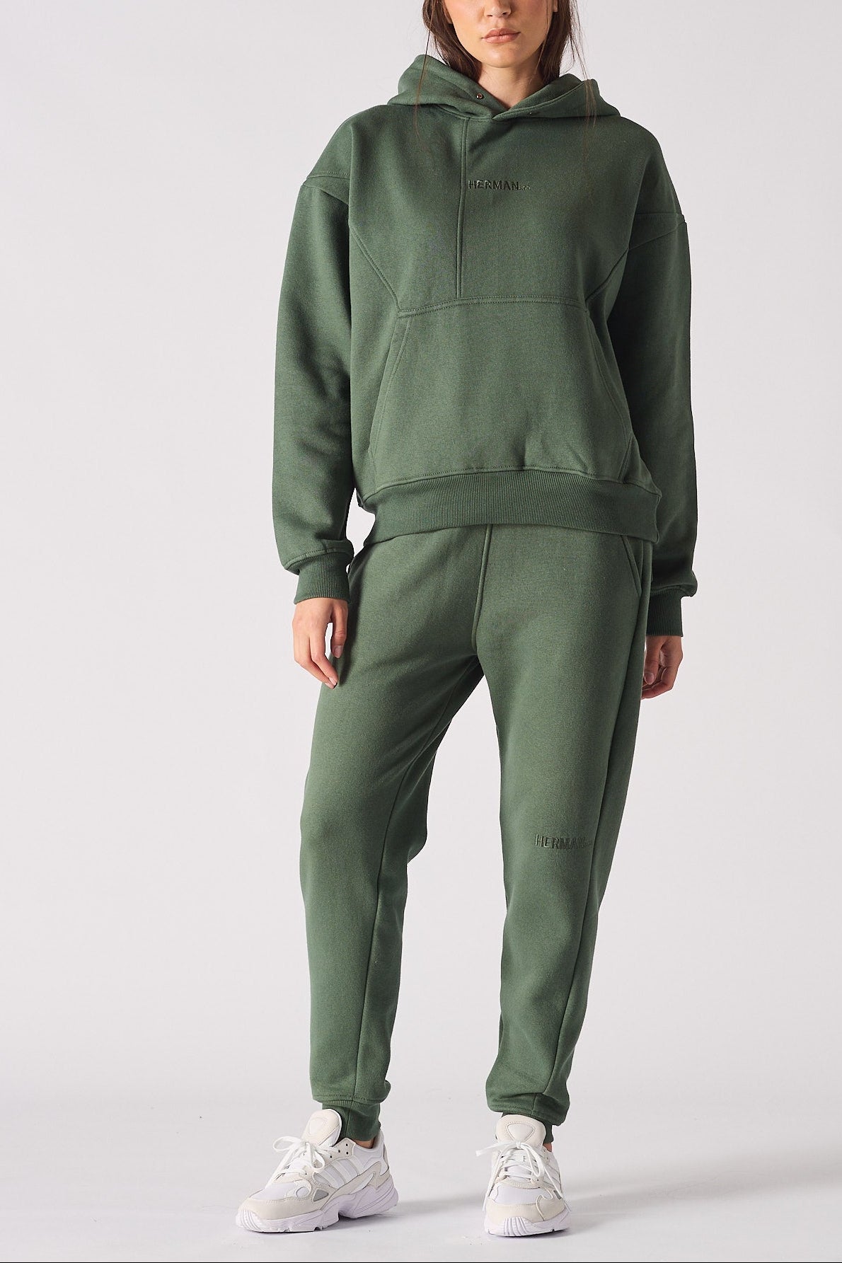 Full front view of a woman posing in a dark green hoodie with matching trousers