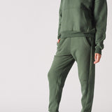 Side view of a woman wearing a dark green hoodie and matching joggers