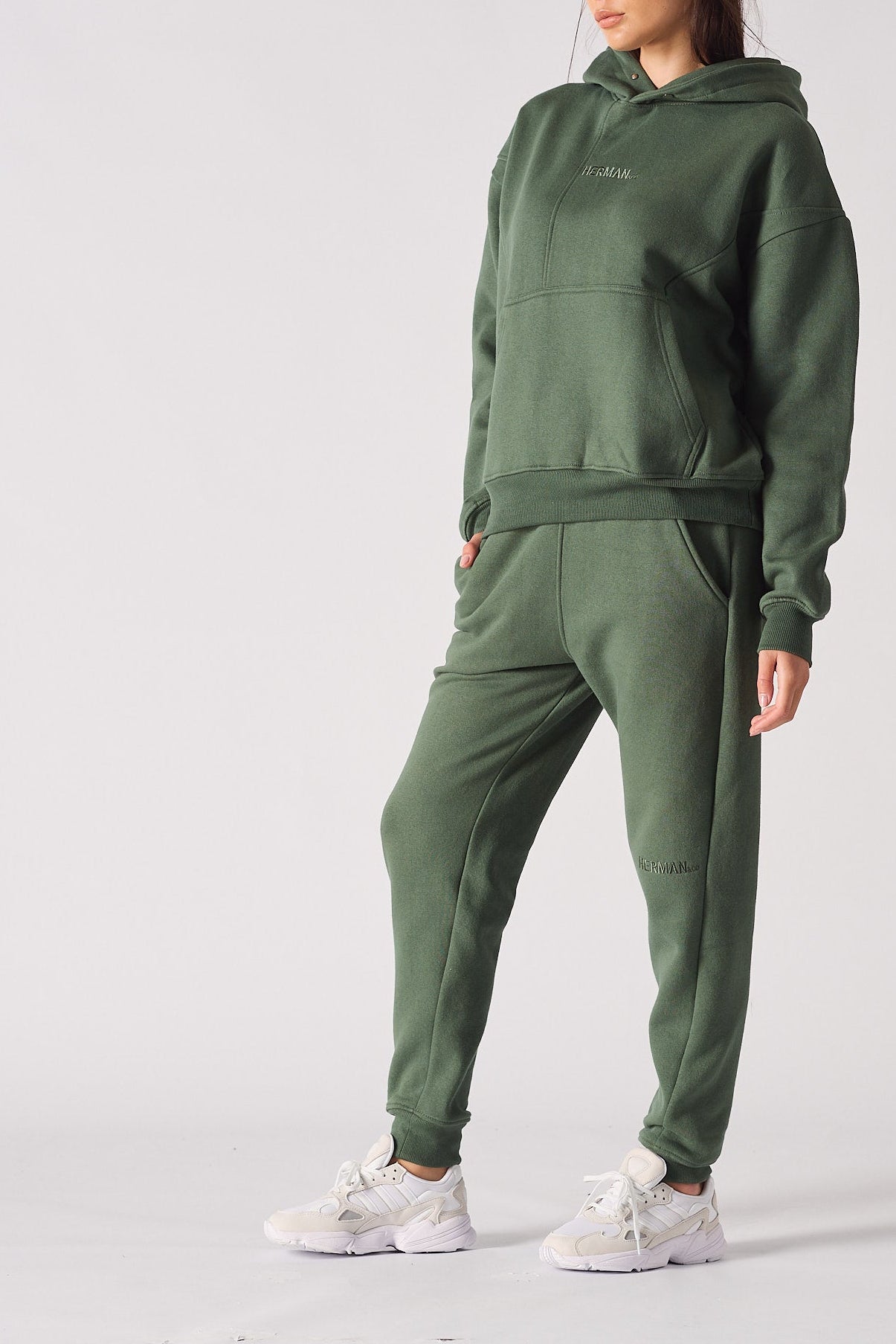 Side view of a woman wearing a dark green hoodie and matching joggers