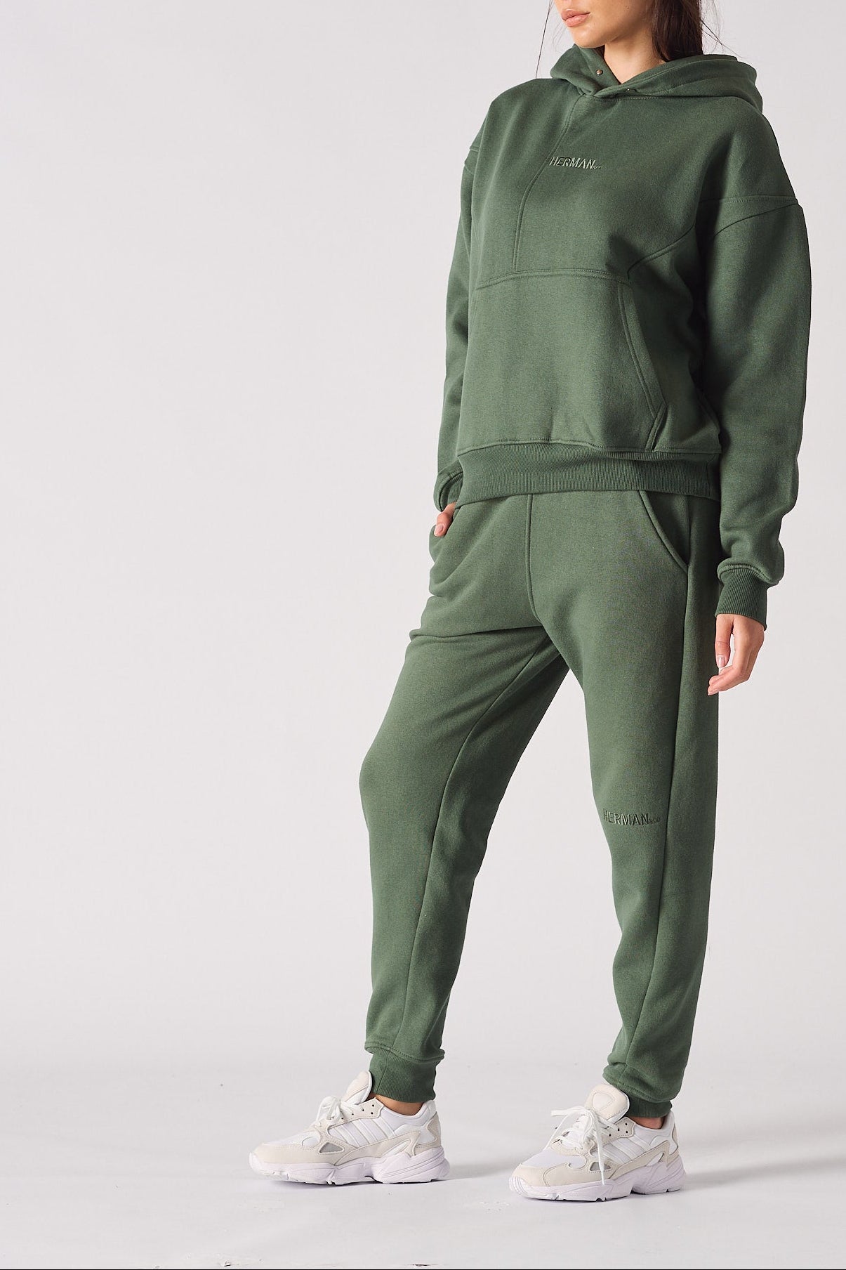 Side view of a woman wearing a dark green hoodie and matching joggers