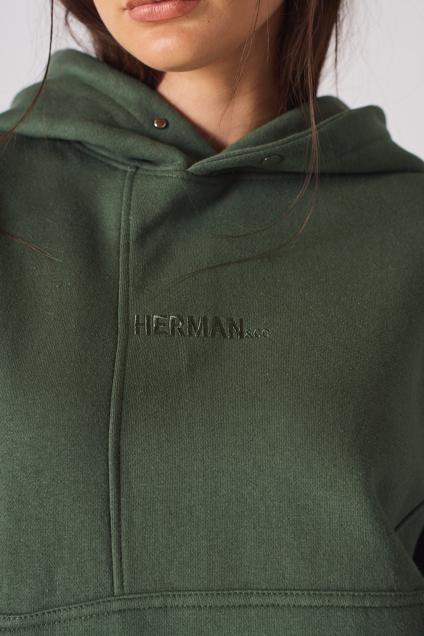 A detailed view of the tonal embroidered insignia on a dark green hoodie