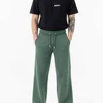 front view of man wearing dark green wide leg joggers with trainers