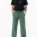 front view of man wearing dark green wide leg joggers with trainers