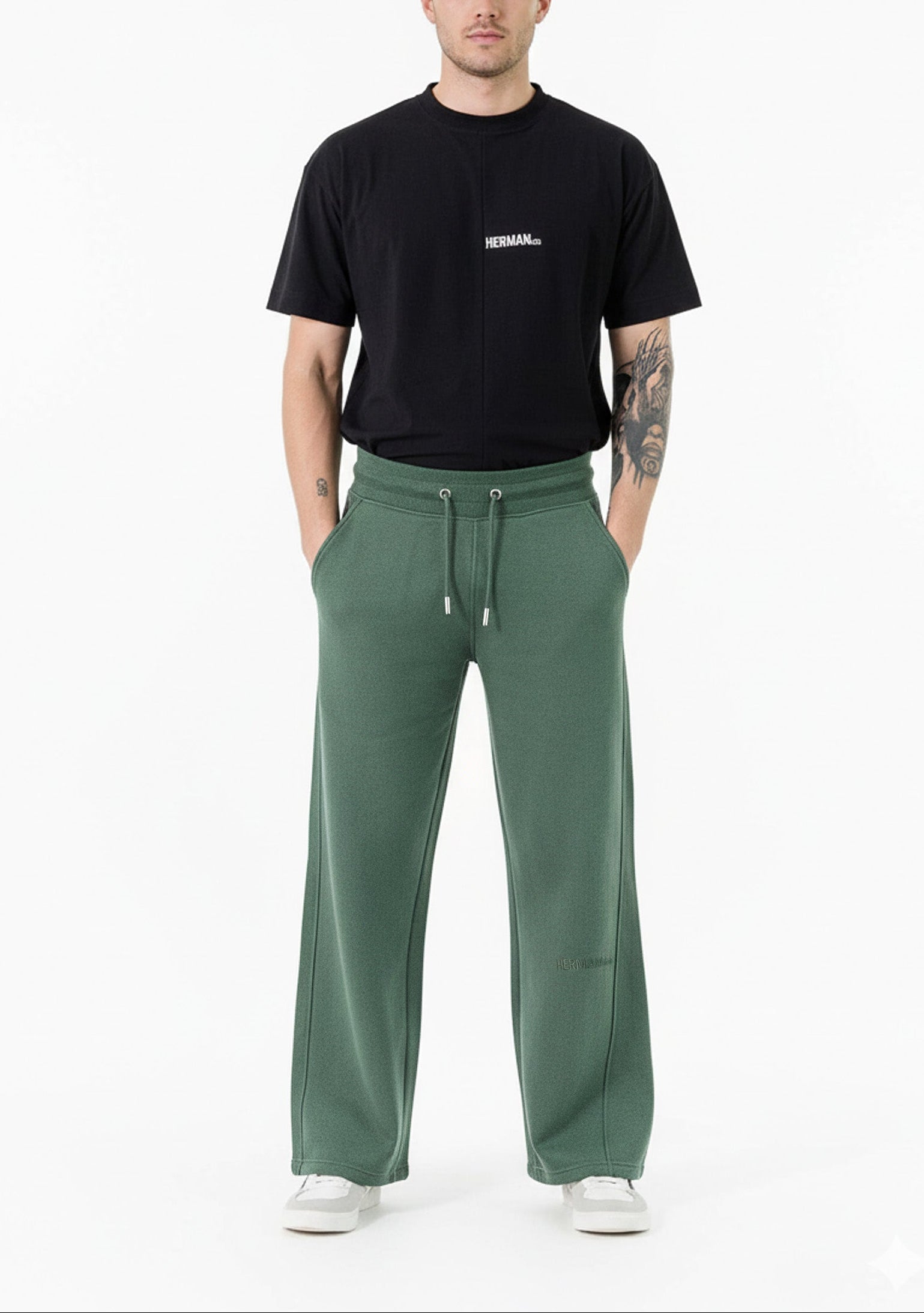 front view of man wearing dark green wide leg joggers with trainers