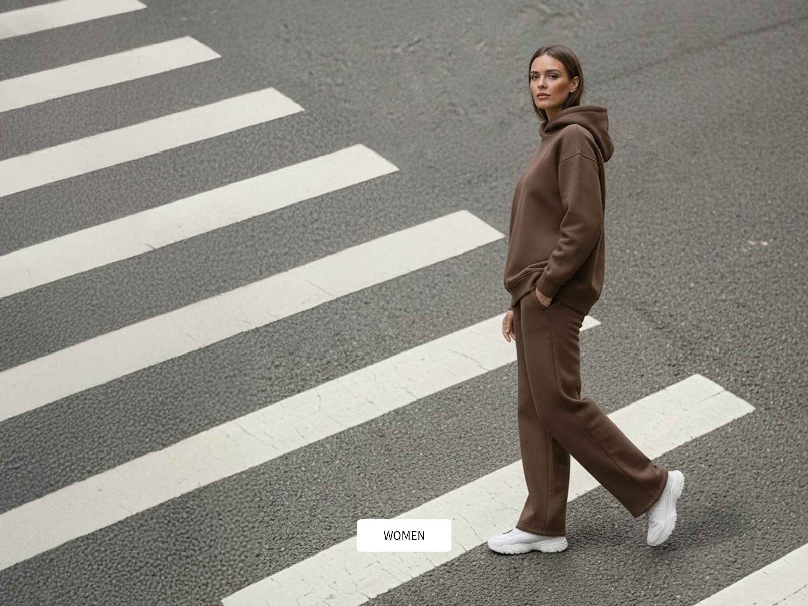 Person wearing a brown tracksuit crossing a zebra crossing