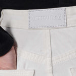 Close-up of the back waistband and logo patch on the distressed jeans for women.