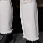 Close-up of the frayed hem and distressed knee detail on the off-white jeans.